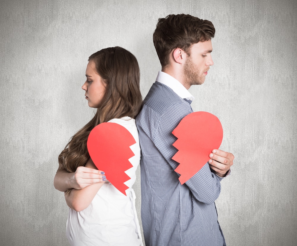 muškarac i žena okrenuti leđima, svaki drži svoj komad prepolovljenog papirnatog srca