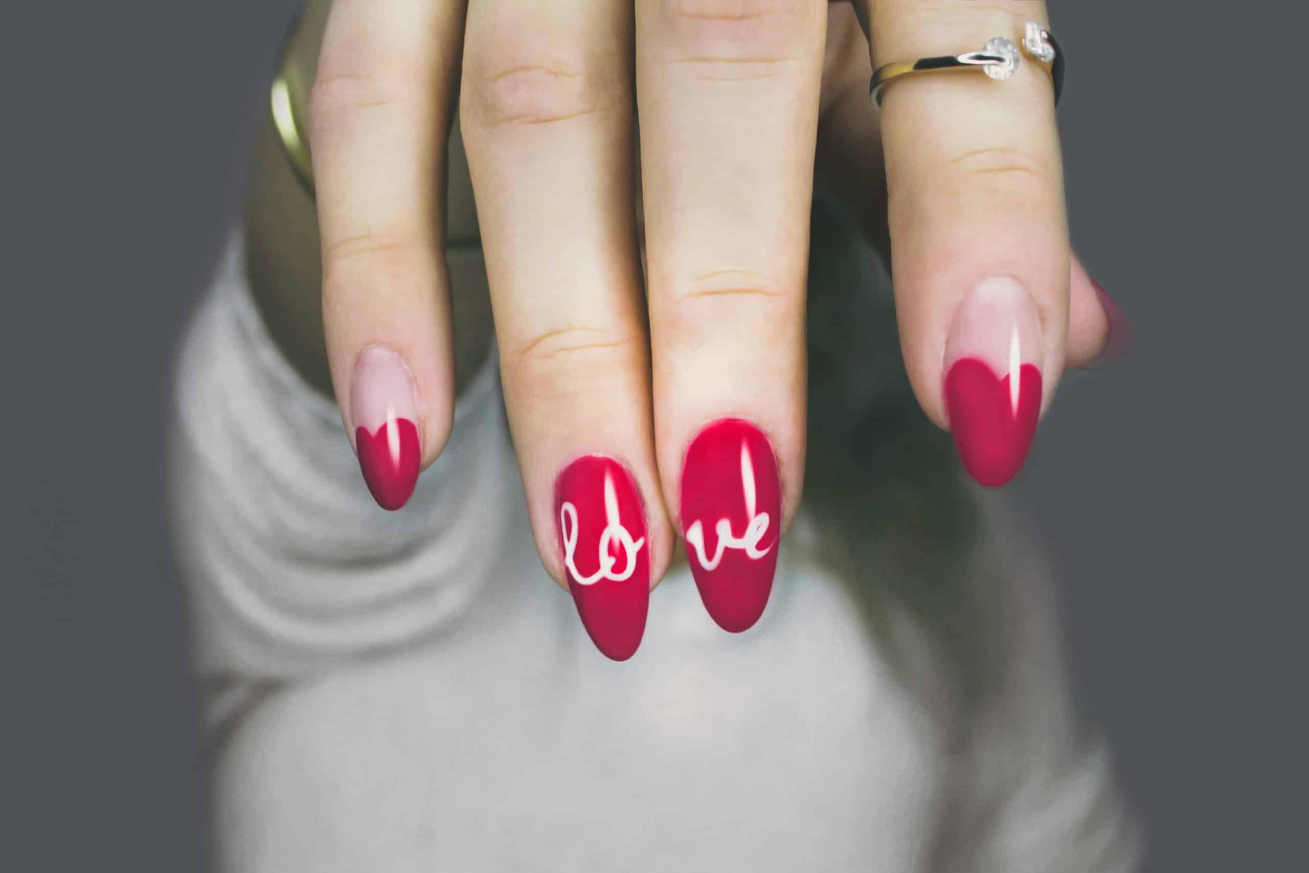 umjetni nokti crvene boje s natpisom "love"